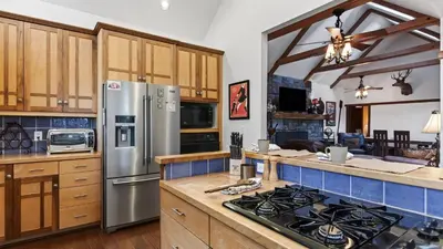 a kitchen with stainless steel appliances and wooden cabinets at Holiday Lake Cabin by AvantStay Large Deck Cozy Fireplace Near Arrowhead Village in Lake Arrowhead