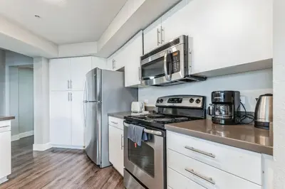 a kitchen with stainless steel appliances and white cabinets at 3BR 2BTH Santa Monica Apartment - Pool, Balcony, Near LAX in Los Angeles