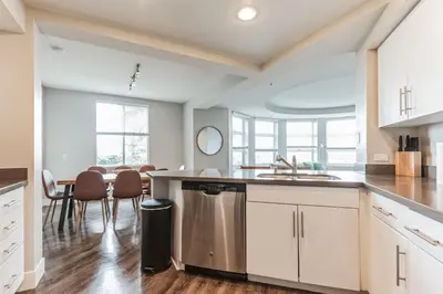 a kitchen with white cabinets and a table with chairs at 3BR 2BTH Santa Monica Apartment - Pool, Balcony, Near LAX in Los Angeles
