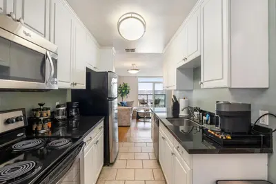 a kitchen with white cabinets and black counter tops at Golden Hour Glow - Stunning 3BR Overlooking the Marina in Los Angeles