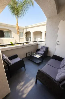a balcony with couches and a table and a palm tree at Serenity Close To Marina Docks - Short Trip To Venice Beach in Los Angeles