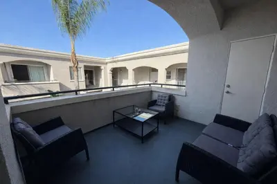 a balcony with couches and a table and a palm tree at Serenity Close To Marina Docks - Short Trip To Venice Beach in Los Angeles