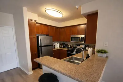 a kitchen with wooden cabinets and a stainless steel refrigerator at Marina Del Rey 2BR-2BA & 1 BR-1BA - Easy Trip To Venice Boardwalk in Los Angeles