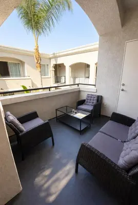 a balcony with a couch and chairs and a palm tree at Marina Breeze Retreat 2BR 2BA - Close To Venice Beach in Los Angeles