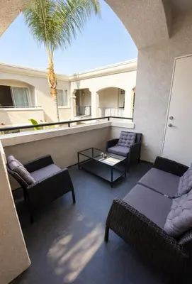 a balcony with couches and a table and a palm tree at Boardwalk & Marina Retreat in Los Angeles