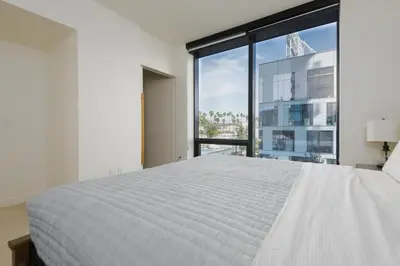 a bedroom with a white bed and a large window at 2Bed Apt View of Hollywood Sign & Rooftop Pool in Los Angeles