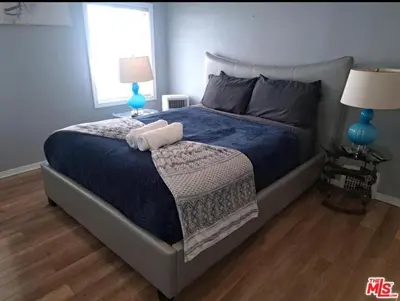 a bedroom with a bed with a blue blanket and two lamps at Residents inn in Los Angeles
