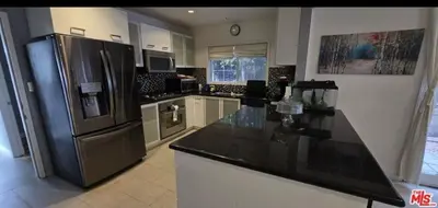 a kitchen with a black counter top and a refrigerator at Residents inn in Los Angeles