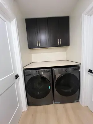 a kitchen with a washer and dryer with black cabinets at Modern Family 3BR Near LAX & Disney in Torrance