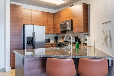 a kitchen with wooden cabinets and a stainless steel refrigerator at Sleek Marina Den, Central, Gym, Pool, King Bed in Los Angeles