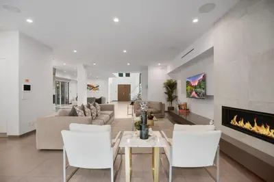 a living room with white chairs and a fireplace at Colgate Vantage in Los Angeles