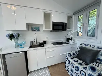 a kitchen with white cabinets and a chair and a sink at Beach House by LA Coast in Torrance