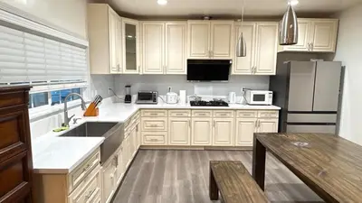 a kitchen with white cabinets and a refrigerator at Cozy 2-Bedroom Retreat Home in East Los Angeles in Hacienda Heights