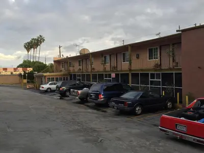 a parking lot with cars parked in front of a building at Highland Park Motel in Los Angeles