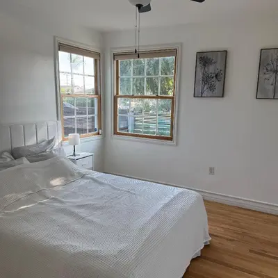 a white bedroom with a bed and two windows at Cozy House in Hewitt