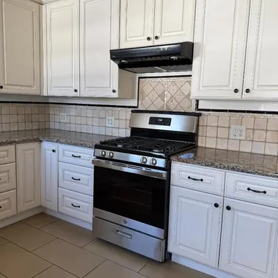 a kitchen with white cabinets and a stove top oven at Cozy House in Hewitt