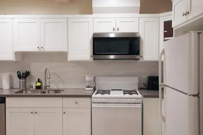 a white kitchen with a stove and a microwave at The Warmwood Retreat in Los Angeles