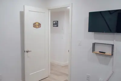 a white hallway with a door and a tv at The Warmwood Retreat in Los Angeles