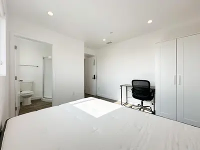 a bedroom with a white bed and a black chair at The 1443 in Los Angeles