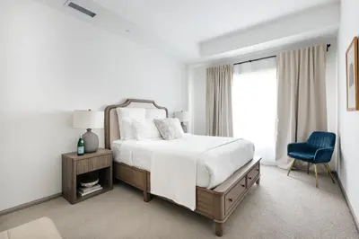 a white bedroom with a bed and a blue chair at Brilliant 2BD condo in Los Angeles