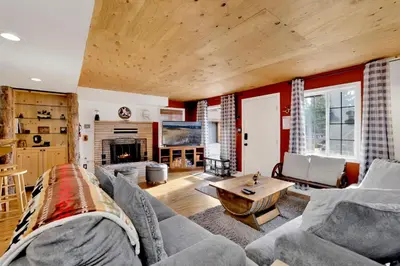 a living room with a couch and a table at Highland Hideaway at Big Bear | Cozy Cabin w/ Private Hot Tub in Big Bear Lake