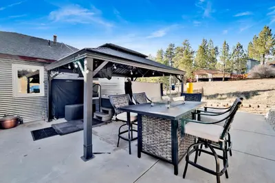 a patio with a table and chairs under a gazebo at Highland Hideaway at Big Bear | Cozy Cabin w/ Private Hot Tub in Big Bear Lake