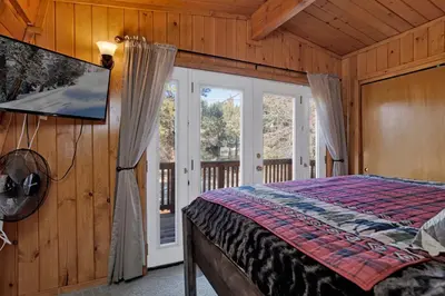a bedroom with a bed and a sliding glass door at The Cave at Big Bear Lake - Adorable Mountain Retreat w/ Hot Tub in Big Bear Lake