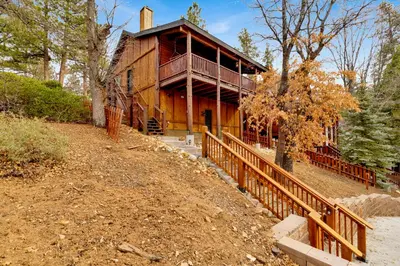 a large wooden house on a hill with a wooden fence at Cielos Nest Cabin | Close to Village and Lake with Hot Tub in Big Bear Lake
