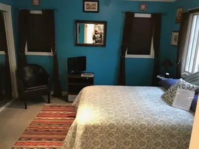 a bedroom with blue walls and a bed and a chair at Elaine's Hollywood Bed & Breakfast in Los Angeles
