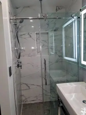 a shower with a glass door next to a sink at Glen Capri Inn and Suites - Burbank Universal in Glendale