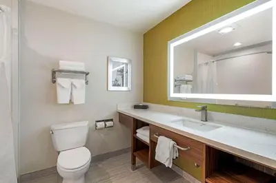 a bathroom with a toilet and a sink and a mirror at Best Western Plus Gardena-Los Angeles Inn & Suites in Gardena
