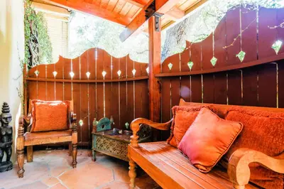 a porch with a wooden bench and a chair at The Emerald Iguana Inn in Ojai