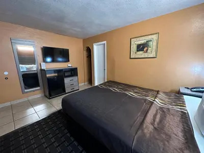 a hotel room with a bed and a television at New Corral Motel in Victorville