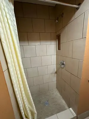 a bathroom with a shower with a shower curtain at New Corral Motel in Victorville
