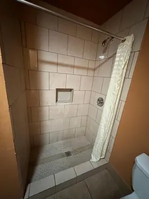 a bathroom with a shower with a toilet at New Corral Motel in Victorville