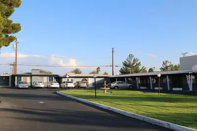 a woman is standing in front of a parking lot at New Corral Motel in Victorville