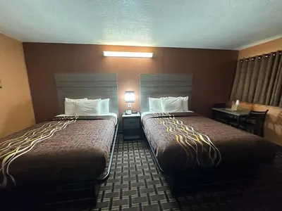 a hotel room with two beds and a table at New Corral Motel in Victorville
