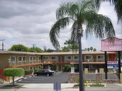 a hotel with a palm tree in front of a parking lot at Fullerton Lodge in Fullerton