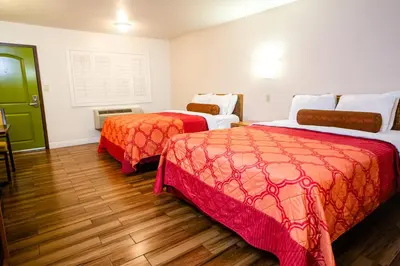 a hotel room with two beds and a green door at Tropic Lodge in Anaheim