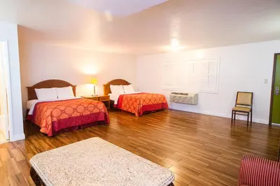 a room with two beds and a table at Tropic Lodge in Anaheim