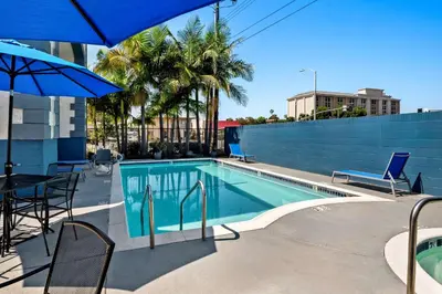a swimming pool with chairs and a table and an umbrella at SureStay Hotel by Best Western Buena Park Anaheim in Buena Park