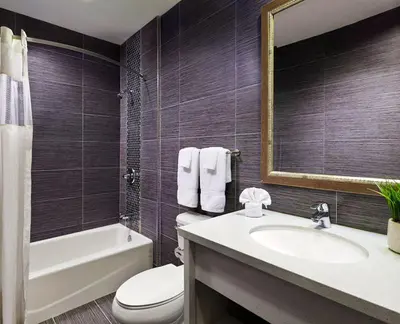 a bathroom with a sink and a toilet and a mirror at American Inn Downey in Downey