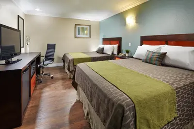a hotel room with two beds and a flat screen tv at American Inn Downey in Downey