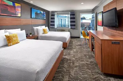 a hotel room with two beds and a flat screen tv at Studio Inn & Suites at Promenade Downey in Downey