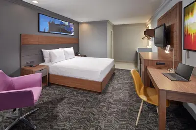 a hotel room with a bed and a desk and a laptop at Studio Inn & Suites at Promenade Downey in Downey