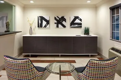 a living room with two chairs and a glass table at Studio Inn & Suites at Promenade Downey in Downey