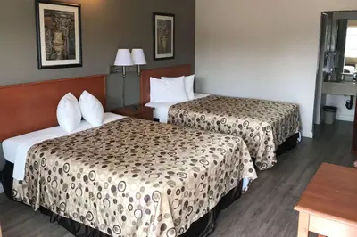 a hotel room with two beds and a table at Rodeway Inn Ontario Mills Mall in Guasti