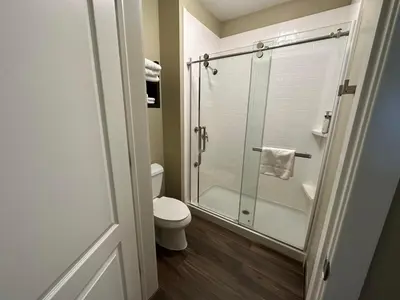 a bathroom with a toilet and a glass shower at Staybridge Suites Anaheim At The Park by IHG in Anaheim