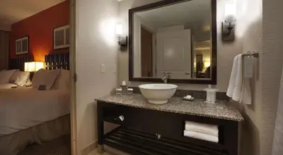 a bathroom with a sink and a large mirror at Embassy Suites Palmdale in Palmdale