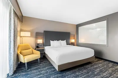 a bedroom with a bed and a chair and a window at Hourglass Hotel, Trademark Collection by Wyndham in Bakersfield